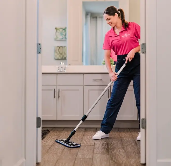 Molly Maid professional cleaning a bathroom floor.