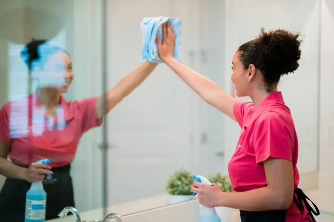 Molly Maid service professional cleaning a bathroom mirror. 