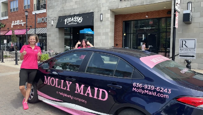 Molly Maid of St. Charles County house cleaning staff standing next to company car.